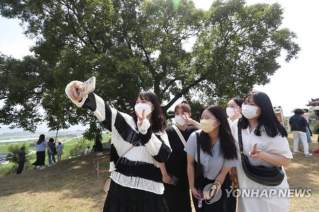 '이상한 변호사 우영우' 팽나무 앞에서 (창원=연합뉴스) 김동민 기자 = 26일 오후 경남 창원시 의창구 대산면 '창원북부리 팽나무' 일대에서 관광객이 기념 촬영하고 있다.  이 나무는 ENA 드라마 '이상한 변호사 우영우'에 '소덕동 팽나무'로 등장했고, 최근 온·오프라인에서 큰 인기를 끌고 있다. 2022.7.26 image@yna.co.kr