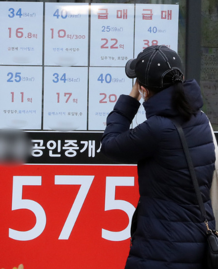 (서울=뉴스1) 장수영 기자 = 13일 서울시 강남구의 한 부동산 공인중개사 사무소에 붙어진 아파트 매물 가격표 앞으로 시민이 지나가고 있다. 2022.2.13/뉴스1