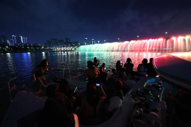 29일 오후 레인보우브릿지 요트페스티벌에 참여한 시민들이 서울 반포한강공원 세빛섬에서 출발한 요트를 타고 반포대교 달빛무지개분수를 배경으로 기념 사진을 찍고 있다. 우상조 기자