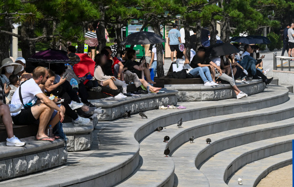 폭염주의보가 발효된 지난 24일 부산 해운대 해수욕장을 찾은 시민들이 그늘 밑에서 햇빛을 피하고 있다. 국제신문 DB