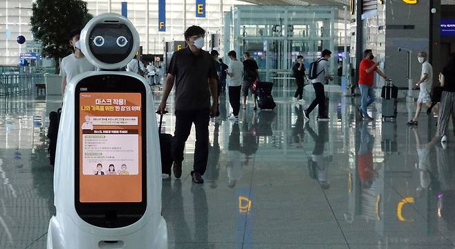 지난달 11일 인천공항 출국장 로봇 화면에 마스크 착용 안내문이 나오고 있다. /연합뉴스