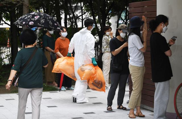 지난달 7일 오전 서울 마포구보건소 선별진료소에 검체검사를 받으려는 시민들이 길게 줄지어 대기하는 가운데 의료진이 폐기물을 들고 이동하고 있다. 홍인기 기자