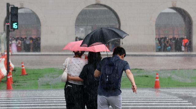 지난 6일 소나기가 쏟아지자 서울 종로구 광화문 인근 횡단보도에서 우산을 쓴 시민들이 황급히 발걸음을 옮기고 있다. 뉴스1