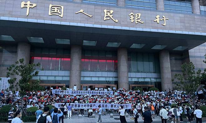 중국 허난성 성도 정저우에 위치한 중국 중앙은행 정저우 지부 앞에서 지난 7월 10일 중국 중앙은행 직원의 부패 혐의를 비난하는 수백 명의 시위대가 시위를 벌이고 있다. 정저우=AFP연합뉴스