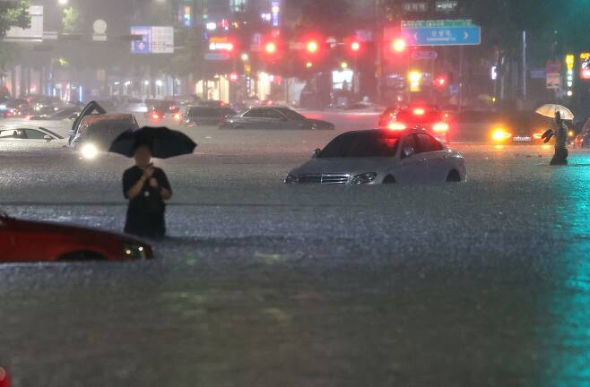8일 밤 서울 강남구 대치역 인근 도로가 물에 잠기면서 침수된 차량을 버리고 운전자들이 대피하고 있다. /연합뉴스