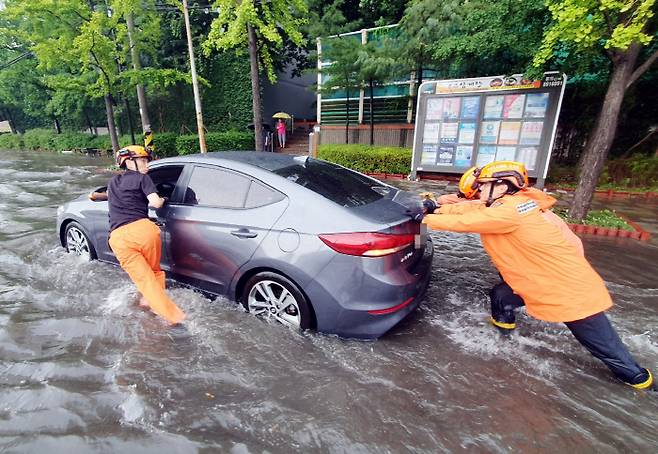 인천지역에 폭우가 내린 8일 인천시 미추홀구 용현동 한 도로에서 소방대원들이 침수된 차량을 안전한 곳으로 옮기고 있다 [사진 제공 = 인천소방본부]