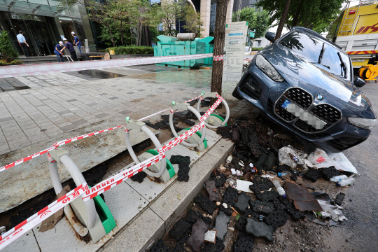 10일 오전 서울 강남역 인근 한 빌딩에서 배수 작업이 진행되고 있는 가운데 침수된 차가 방치되어 있다.  연합뉴스