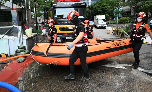 10일 서울 강남역 인근에서 119 특수구조대원들이 주황색 소방 구명보트를 들고 폭우로 휩쓸린 실종자들을 찾기 위해 강남빌딩 지하주차장 입구로 들어가고 있다 . 배우한 기자
