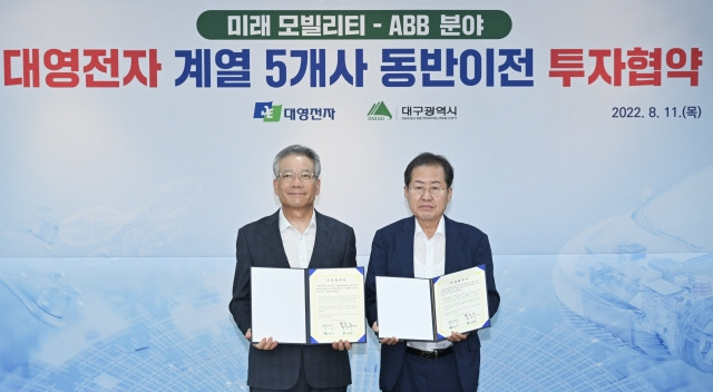 홍준표 대구시장(오른쪽)과 백서재 대영전자 회장이 11일 대구시청에서 대영전자 계열 5개사 본사 동반이전 및 통합연구소 구축 투자협약식을 가진 뒤 협약서를 들어 보이고 있다. 대구시 제공