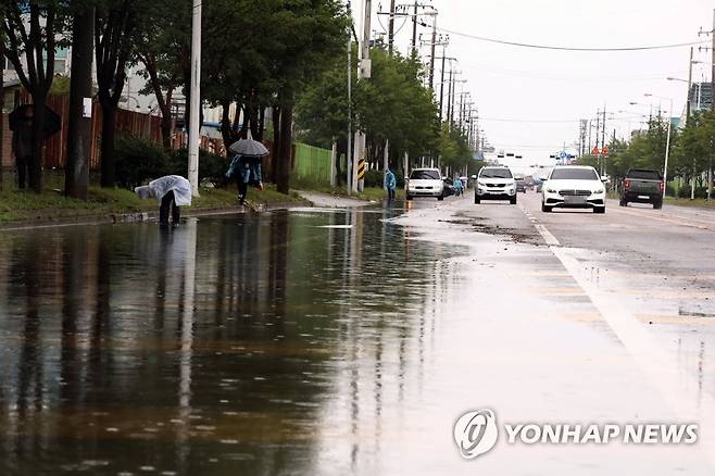 도로 복구 작업 중인 군산시 (군산=연합뉴스) 나보배 기자 = 폭우 특보가 내려진 11일 오후 전북 군산시 오식도동의 한 도로에서 군산시 공무원들이 배수 작업을 하고 있다. warm@yna.co.kr