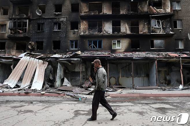 우크라이나 동부 도네츠크주 시베르스크에 전소된 건물들 앞에 한 남성이 담배를 피우면서 지나가고 있다. 2022.07.22 ⓒ AFP=뉴스1 ⓒ News1 정윤미 기자