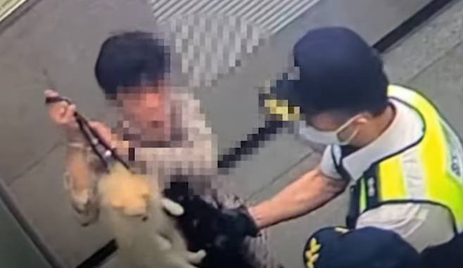 지난 2일 경기 평택역에서 한 남성이 목에 줄을 맨 포메라니안의 목줄을 공중으로 들어올리고 있다. /케어