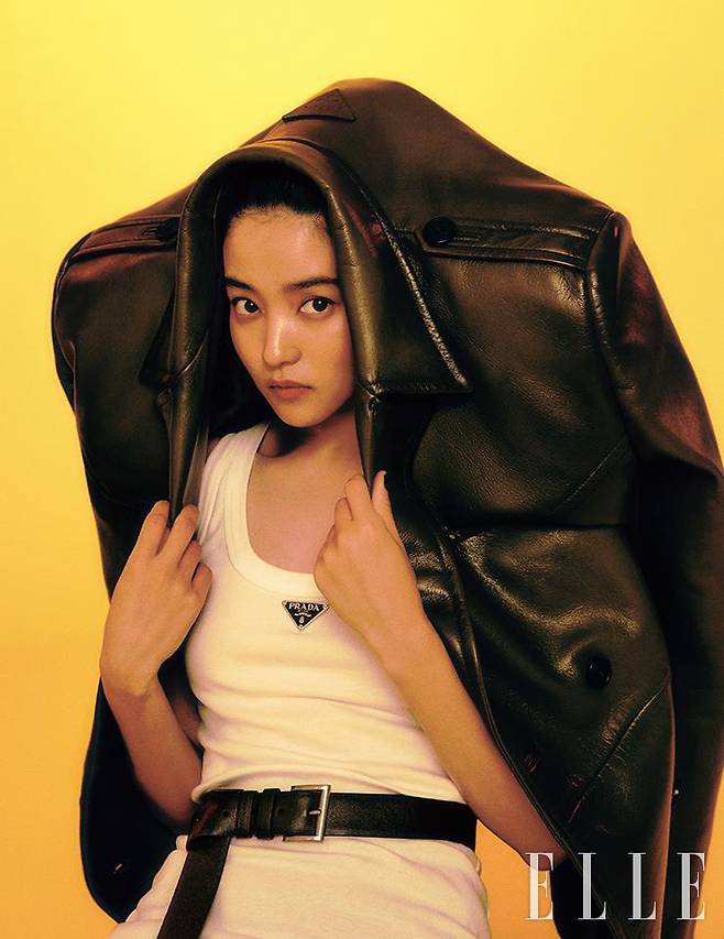 브랜드 시그너처 로고를 장식한 화이트 탱크톱과 벨트, 그러데이션으로 포인트를 준 가죽 재킷은 모두 Prada.