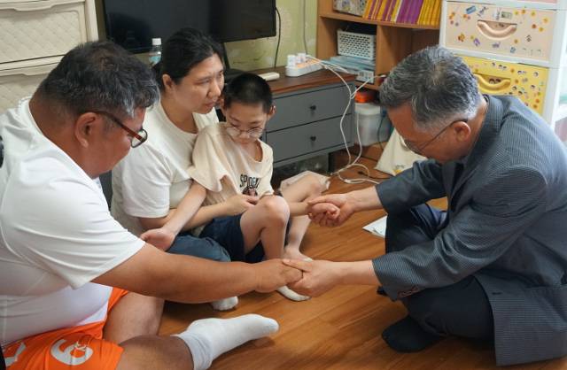 이구일(오른쪽) 서산제일감리교회 목사가 지난달 14일 충북 청주의 한 아파트에서 기현이네 가족과 함께 기도하고 있다. 왼쪽부터 기현이의 아버지, 어머니, 기현이, 이 목사.