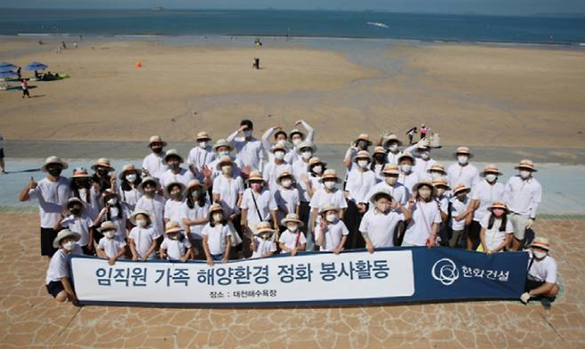 한화건설 임직원 가족들이 대천해수욕장 해양환경 정화 봉사활동에 참여하고 기념사진을 촬영하고 있다. [사진 = 한화건설]
