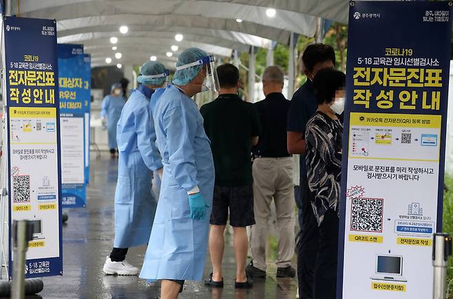 지난 11일 오후 광주 서구 5·18민주화운동 교육관에 재설치 운영에 들어간 임시선별검사소에서 의료진이 코로나19 검사를 받으려는 시민들의 문진표 작성을 돕고 있다. 연합뉴스