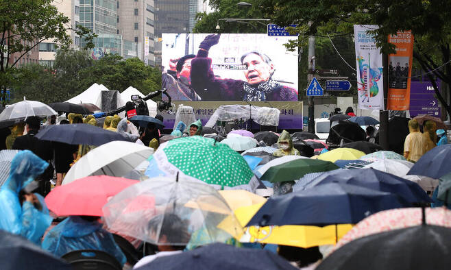 14일 저녁 서울 중구 청계천 광통교 일대에서 열린 제10차 ‘세계 일본군 위안부 피해자 기림의 날’ 나비문화제에서 우산을 쓴 참가자들이 고 김학순 할머니의 생전 모습을 영상으로 만나고 있다. 백소아 기자