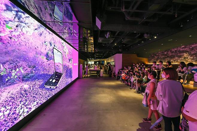 지난 13일 일본 도쿄의 갤럭시 하라주쿠에서 소비자들이 ‘갤럭시Z플립4xBTS’ 디지털 영상을 관람하고 있다. 사진 삼성전자