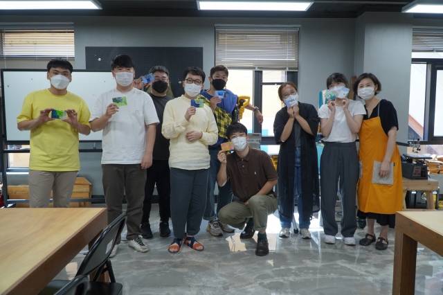 ‘2022 청년연합수련회'에 참가한 청년들이 전북 전주시새활용센터 ‘다시봄 '비닐클링' 수업을 마치고  자신이 만든 비닐 카드지갑을  들며 활짝 웃고 있다. 기장청년연합회 제공.