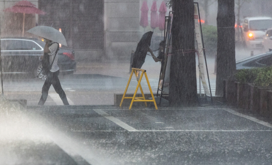 수도권에 물폭탄이 쏟아진 지난 8일 오후 서울 여의도에서 퇴근길을 나선 직장인들이 비를 피하기 위해 사투를 벌이고 있다. 연합뉴스