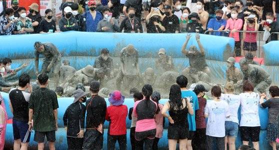 지난달 31일 충남 보령 대천해수욕장 일대에서 열리고 있는 보령해양머드박람회장에서 비가 오락가락하는 날씨 속에서 관람객들이 머드를 뿌리며 놀고 있다. 연합뉴스