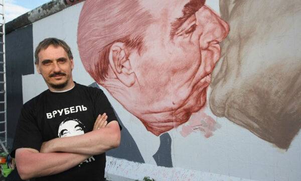 독일 베를린의 명물인 벽화 ‘형제의 키스’ 앞에 선 러시아 화가 드미트리 브루벨. 사진은 2009년 오래돼 칠이 벗겨지는 등 훼손된 그림을 복원할 때의 모습이다. 게티이미지 제공