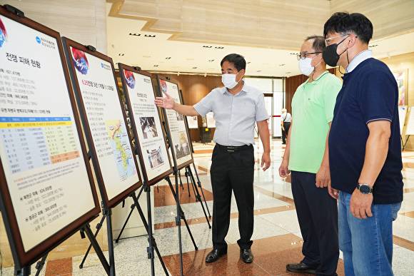 BNK경남은행 본점을 방문한 지역민들(오른쪽)이 16일 BNK경남은행 본점 1층 로비에서 6.25 한국전쟁과 태극기 사진 전시회를 관람하고 있다. [사진=BNK경남은행]