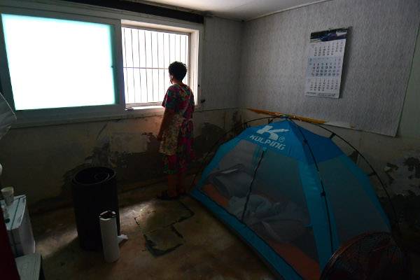 15일 서울 동작구 상도동 다세대주택에서 집주인이 반지하 세입자 방을 정리하던 중 창 밖을 바라보고 있다. 해당 방의 세입자는 지난 8일 기록적인 폭우로 침수 피해를 입은 뒤 텐트를 설치한 채 지내고 있다. 최현규 기자