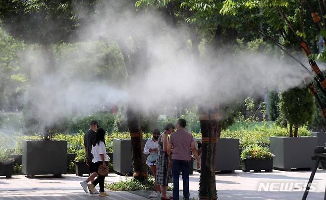 [서울=뉴시스] 이영환 기자 = 무더위가 기승을 부린 5일 오후 서울 중구 세종대로에 설치된 쿨링 포그에서 관광객들이 잠시 휴식을 취하고 있다. 2022.08.05. 20hwan@newsis.com