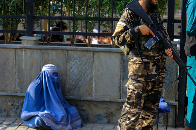 ▲지난달 27일(현지시각) 아프가니스탄 카불에서 탈레반 전사가 총을 들고 서 있는 가운데 머리부터 발끝까지 가리는 복식(부르카)을 착용한 한 여성이 구걸하고 있다. ⓒEPA=연합뉴스 