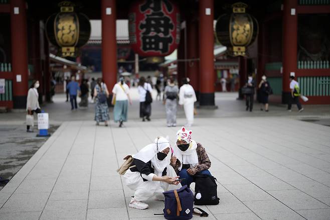 지난 6월10일 일본 도쿄의 아사쿠사 지구 쇼핑 거리에서 마스크를 쓴 외국인 관광객들이 셀카를 찍고 있는 모습. AP뉴시스