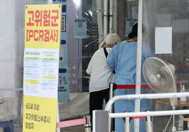 19일 서울 마포구 보건소 코로나19 선별진료소를 찾은 한 어르신이 보건소 관계자의 부축을 받아 검사 장소로 향하고 있다.  연합뉴스