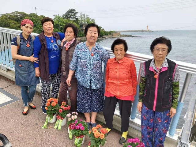 김여나(왼쪽) 작가가 부산광역시 기장군 해녀들과 기념 촬영을 하고 있다.