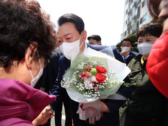 지난 5월 당시 윤석열 대통령 당선인이 1기 신도시 현안 점검을 하면서 아파트 주민으로부터 꽃다발을 받고 있다. 연합뉴스