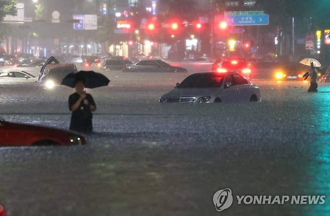 지난 8일 밤 서울 강남구 대치역 인근 도로가 물에 잠기면서 침수된 차량을 버리고 운전자들이 대피하고 있다. [연합뉴스 자료사진]