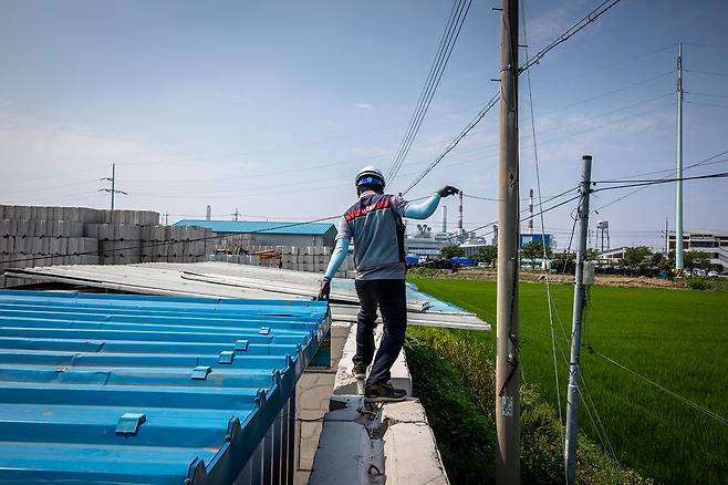 전신주에 닿기 위해 높이 2m 넘는 담벼락 위를 아슬아슬하게 걸어가는 최낙규씨.ⓒ김흥구