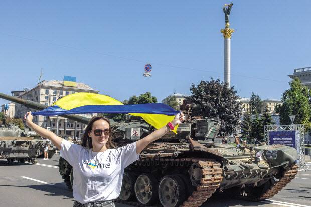 러시아가 우크라이나를 전면 침공한 지 정확히 6개월째가 되는 날이자 우크라이나가 옛 소비에트연방(소련)에서 독립을 선언한 지 31주년이 되는 날인 24일(현지시간) 우크라이나 수도 키이우 중심부의 크레샤티크 거리에서 한 우 크라이나인 여성이 우크라이나 국기를 들고 전투 중 우크라이나군이 파괴·노획한 러시아 장갑차 앞에서 포즈를 취하고 있다.[EPA]