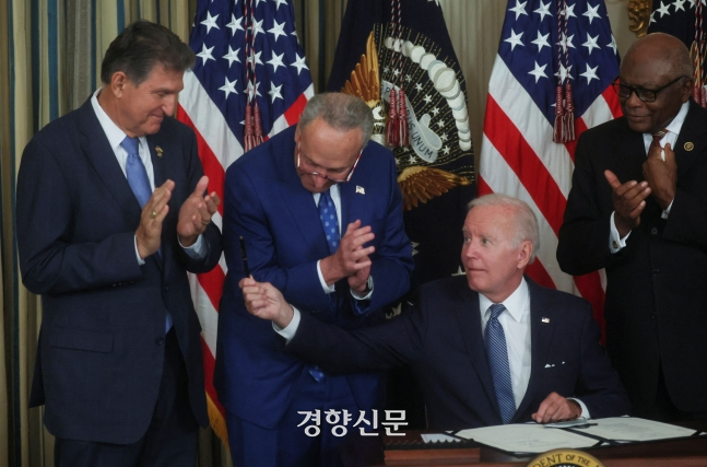 조 바이든 미국 대통령이 지난 16일 백악관에서 열린 인플레이션감축법(IRA) 에 서명한 뒤 이 법안 통과에 결정적 역할을 한 조 맨친 상원의원에게 서명한 펜을 건네주고 있다. 로이터/연합뉴스.