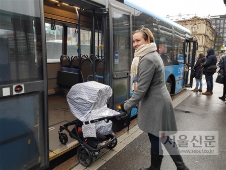 지난달 30일(현지시간) 핀란드 헬싱키 센트럴스테이션 앞 버스 정류장에서 피리타 발코넨이 아이를 태운 유모차와 함께 버스 후문으로 탑승하고 있다. 헬싱키에서는 유모차를 동반하면 대중교통 운임료를 내지 않아도 된다.헬싱키 박재홍 기자 maeno@seoul.co.kr