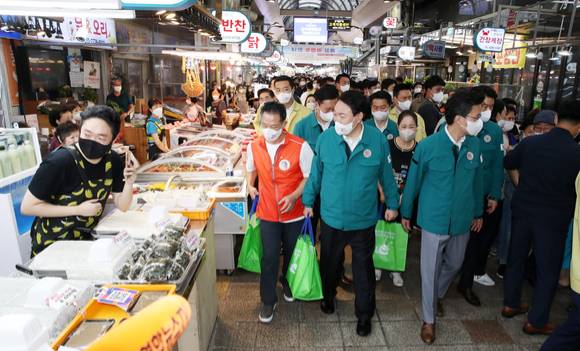 윤석열 대통령이 지난달 25일 서울 강동구 암사종합시장을 방문해 한 반찬가게에서 온라인으로 주문된 상품을 공동배송센터로 옮기는 등 배송 체험을 하고 있다. [사진=뉴시스]