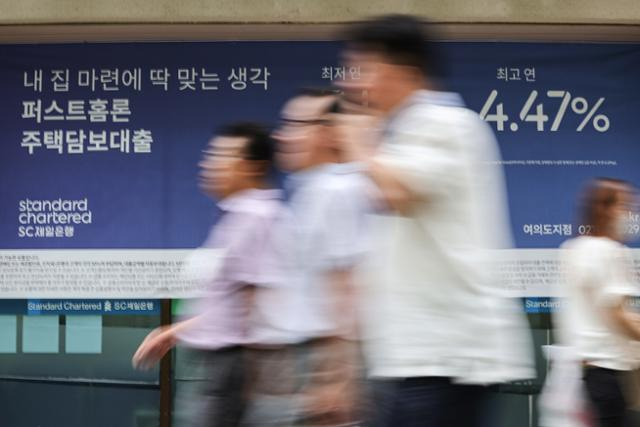 서울 시내 한 은행에 붙은 대출 관련 광고 앞을 지나는 시민들. 연합뉴스