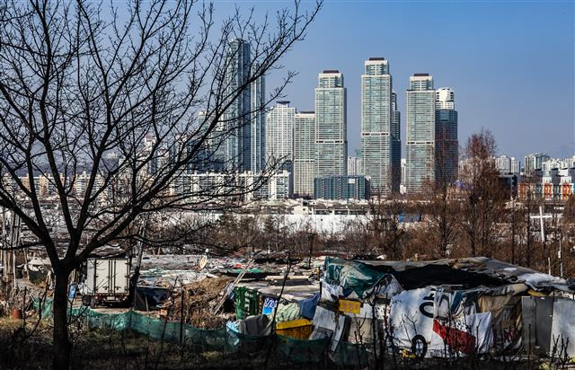 - 서울 강남구 구룡마을과 그 너머로 보이는 양재천변의 초고층 아파트숲.구룡마을에서는 개발을 둘러싸고 주민 간 갈등이 빚어지고 있다.