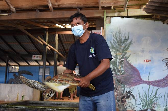 A researcher holds up an injured sea turtle to explain the recovery process to the visitors at Sea Turtle Research and Conservation Center, on March 28. (Kim Hae-yeon/ The Korea Herald)