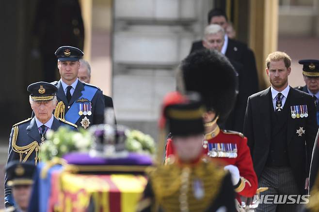 [런던=AP/뉴시스] 찰스 3세 영국 국왕과 윌리엄·해리 왕자가 14일(현지시간) 영국 런던 버킹엄궁에서 엘리자베스 2세 여왕의 웨스트민스터 사원으로 운구 행렬을 따라가고 있다. 2022.09.14.
