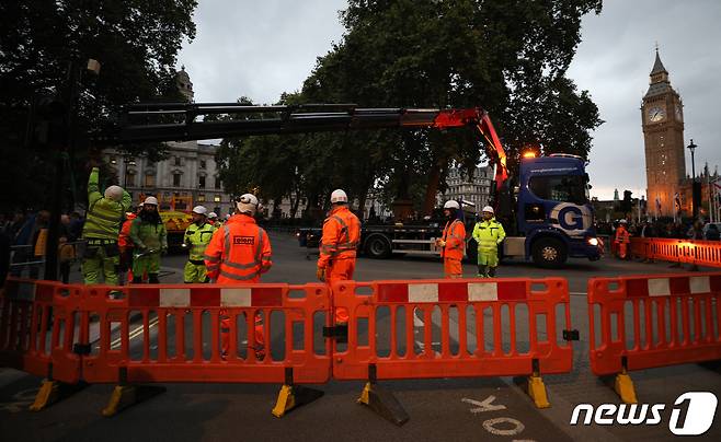 엘리자베스 2세 여왕 국장을 하루 앞둔 18일 오후(현지시간) 영국 런던 웨스트민스터 사원 인근에서 인부들이 장례 행렬을 위해 신호등을 제거하고 있다. 2022.9.19/뉴스1 ⓒ News1 안은나 기자