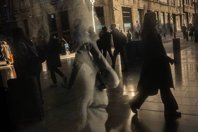 지난 17일(현지시간) 영국 런던 패딩턴역에서 시민들이 엘리자베스 2세 여왕의 그림 앞을 지나가고 있다. 게티이미지