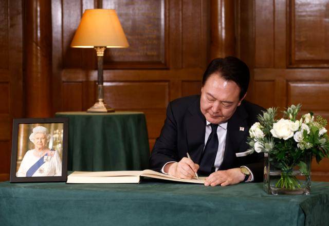 윤석열 대통령이 19일 영국 런던 웨스트민스터에 위치한 처치하우스를 방문해 엘리자베스 2세 영국 여왕의 조문록을 작성하고 있다. 런던=AP 연합뉴스