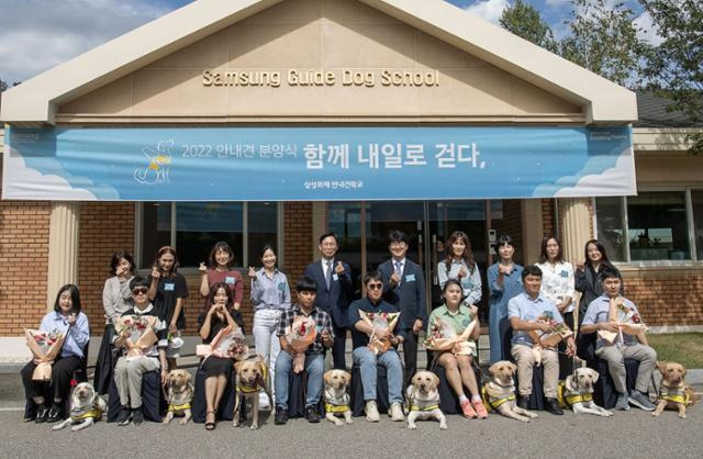 20일 경기 용인시 삼성화재 안내견 학교에서 열린 '함께 내일로 걷다,' 행사에서 시각장애인 파트너와 이들과 함께 새롭게 안내견 활동을 시작하는 안내견, 퍼피워커(자원봉사자), 삼성화재 안내견 학교 관계자들이 기념 촬영을 하고 있다. 삼성전자 제공