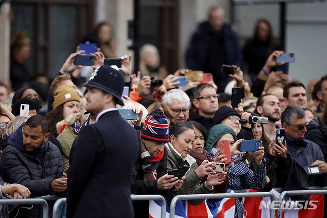 [런던=AP/뉴시스] 19일 오전 (현지시간) 영국 런던에서 고 엘리자베스 2세 영국 여왕의 추모객들이 포차(砲車)에 실려 웨스트민스터 사원으로 운구될 여왕을 기다리고 있다. 2022.09.19.