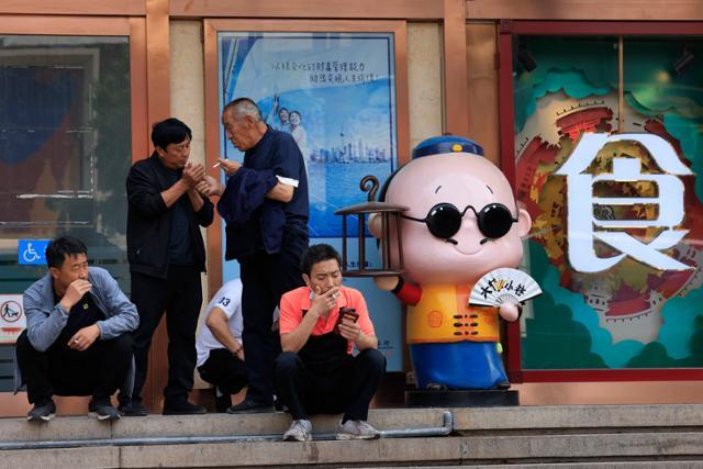 지난해 5월 11일 중국 베이징 왕푸징의 식당 앞 거리에서 주민들이 모여 앉아 담배를 피우고 있다. 베이징=AP 연합뉴스